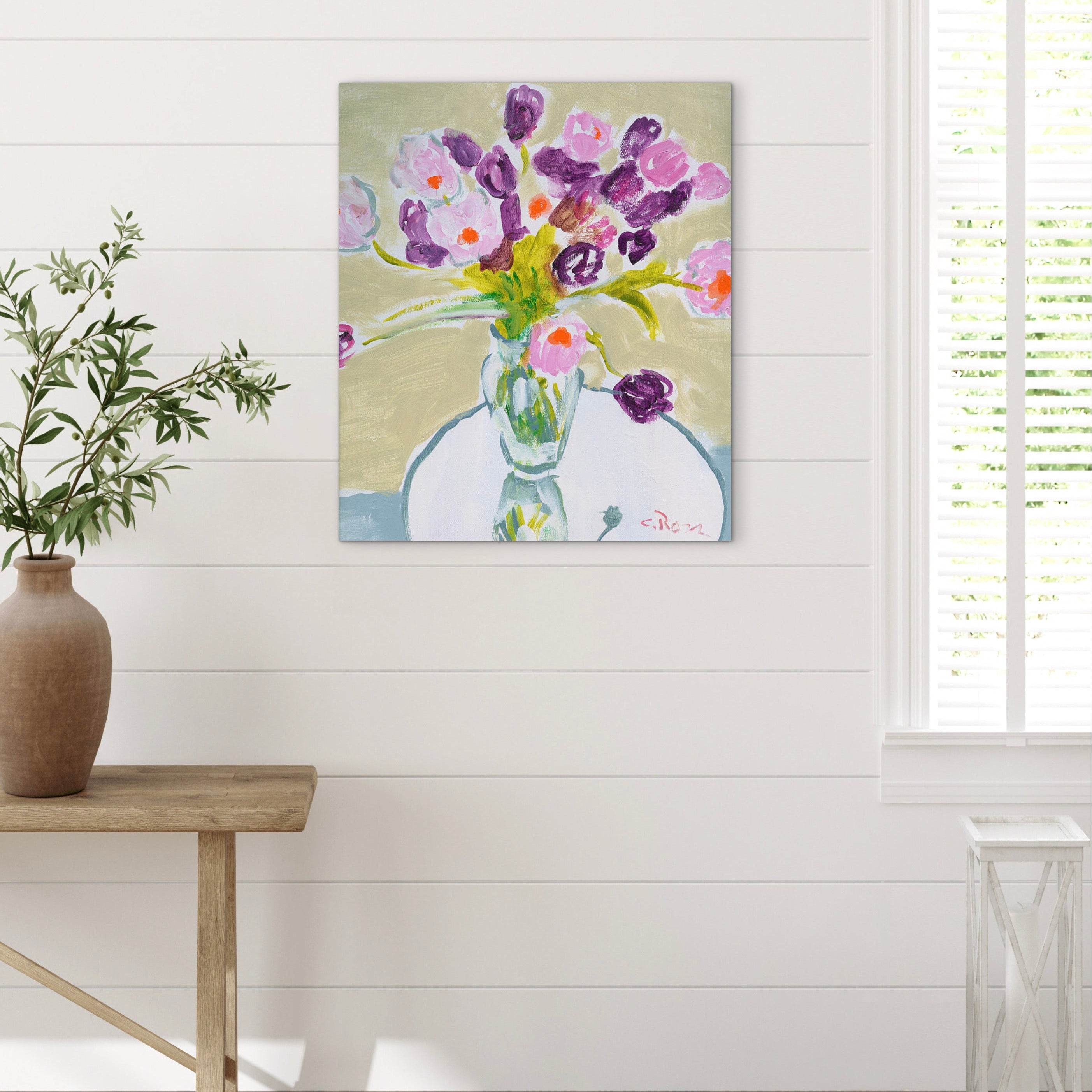 Painting of flowers on a wall in a room with a wooden table and plant.