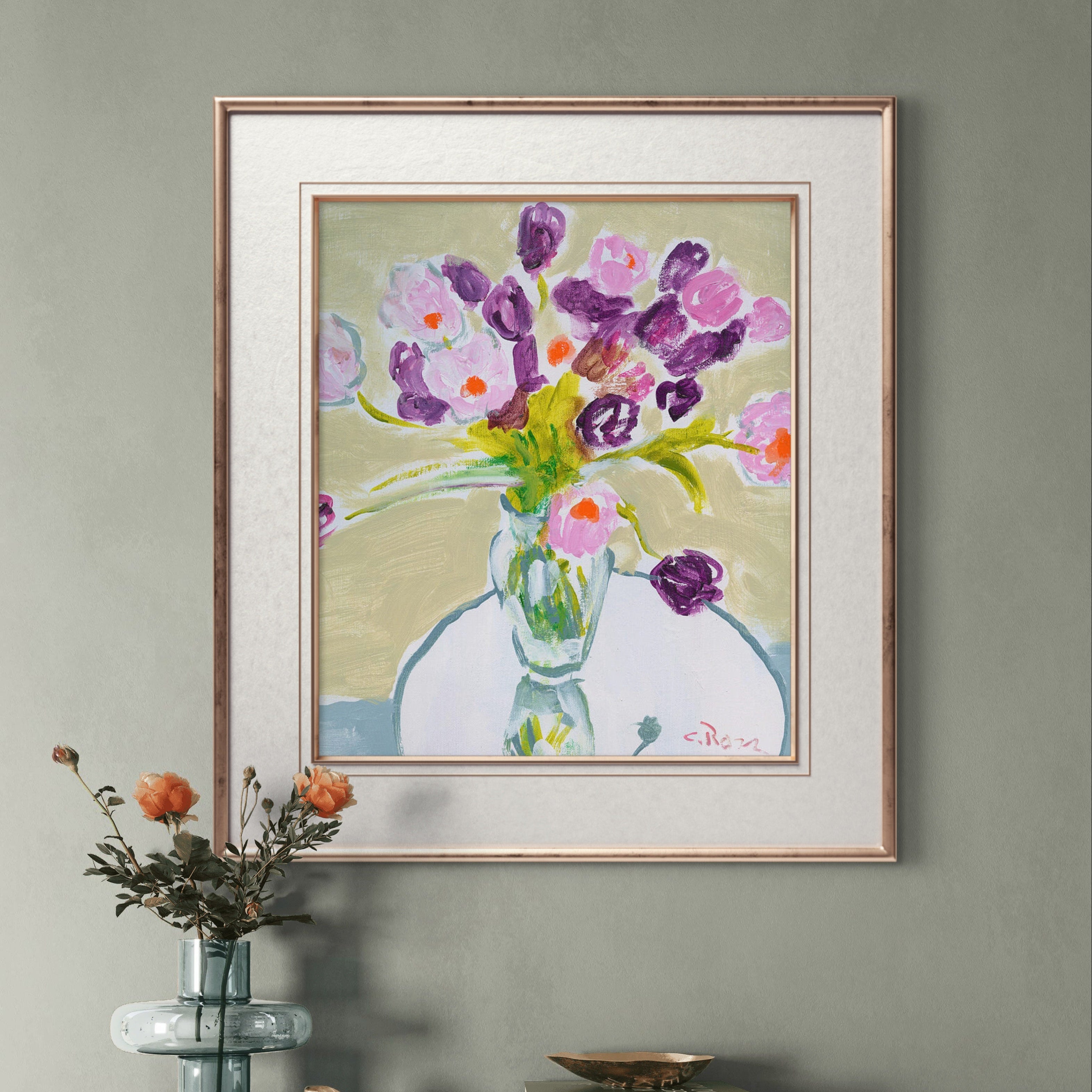 Framed painting of flowers on a wall above a wooden cabinet.